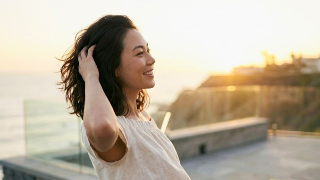 美しい朝焼けを見下ろす丘の上で、落ち着いた色のマキシワンピースを着た洗練された魅力のある20代後半のシングルマザー。
