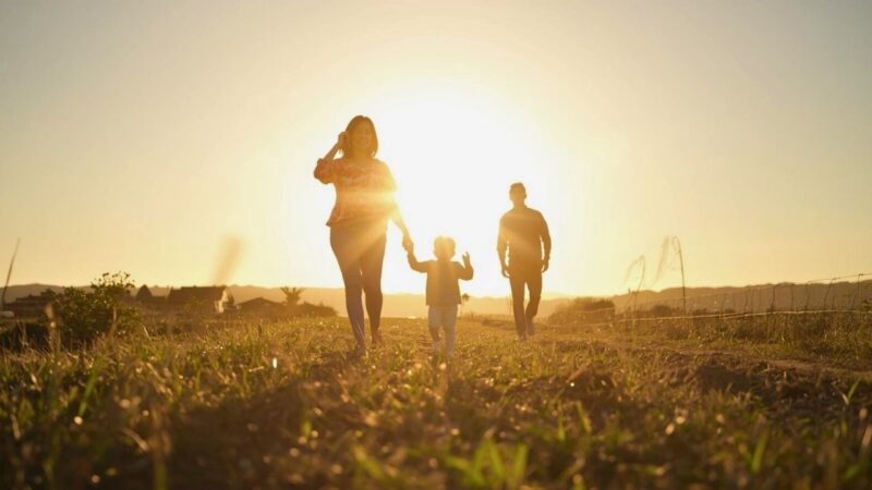 明るい未来に向かって歩く母と子、そして男性の後ろ姿。手当からの卒業と新しい幸せを表現