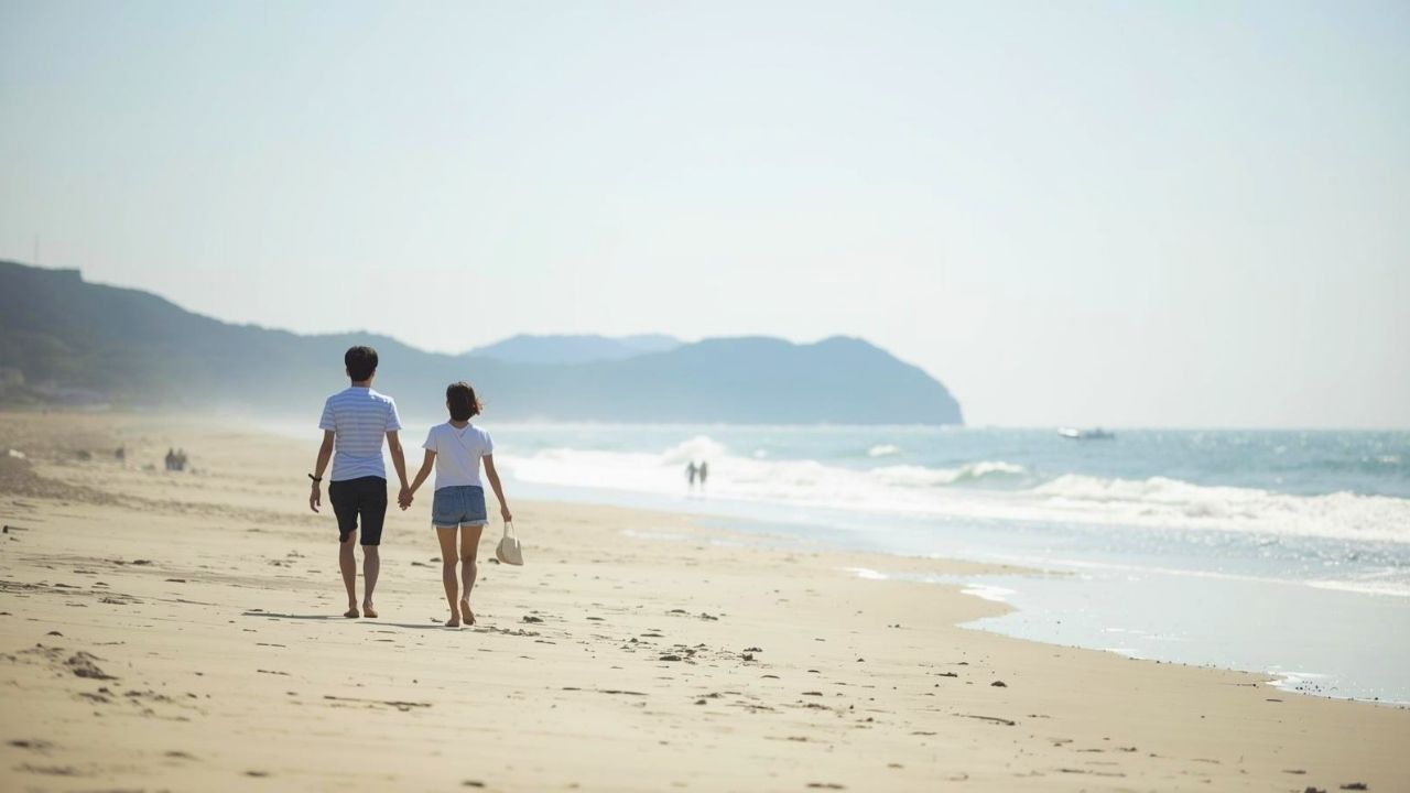 婚活で結ばれたカップルが砂浜を幸せそうに散歩している